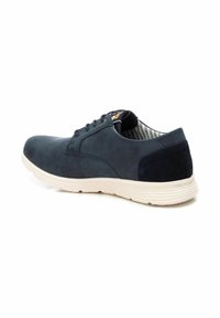 Zapatos de ante de color azul marino con un acabado liso, que cuentan con una suela de goma blanca y un forro a rayas. Cierre de cordones con seis ojales y un acento en el tacón texturizado.