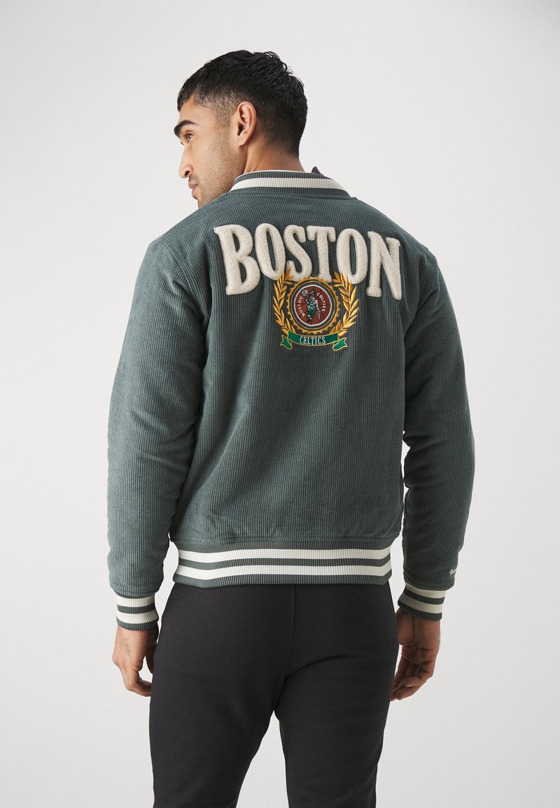 Giacca di velluto a coste verde con grande scritta "BOSTON", logo ricamato con alloro e polsini e orlo a righe in maglia.