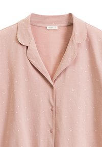 Miękki różowy top do piżamy z małymi białymi gwiazdkami i półksiężycami, z kołnierzykiem w szpic i trzema guzikami z przodu.