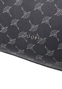 Czarna torebka skórzana o teksturowanej powierzchni z powtarzającym się jasnoszarym wzorem kwiatowym oraz srebrnym detalem z logo. Ma gładkie wykończenie i wyraźnie zarysowany kszta�łt.