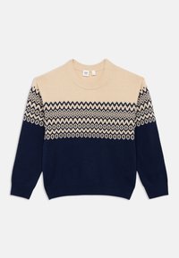 Beige og marineblå strikket genser med geometriske mønstre på den øverste delen, rund halslinning og lange ermer. Myk tekstur, uformell passform.