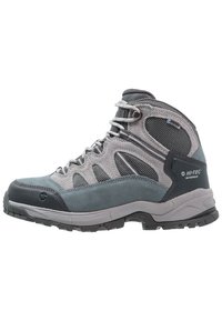Scarpa da trekking grigia realizzata con una combinazione di materiali in suede e mesh, suola in gomma testurizzata e occhielli metallici per una vestibilità sicura.