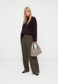 Ylipitkä burgundy neule, oliivinvihreät laivastohousut, mustat ballerinat ja beige käärmeennahkakuosiselaukku. Sileä neulepinta, moderni muotoilu.