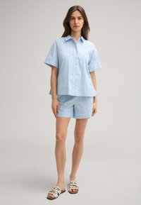 Helles blaues Hemd mit weißen Streifen, kurzärmlig, kombiniert mit passenden Shorts; zeichnet sich durch eine lockere Passform und weichen Stoff aus.