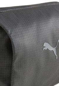 Gray textured bag with a smooth finish, featuring a prominent silver Puma logo on the side. Designed for durability and versatility.