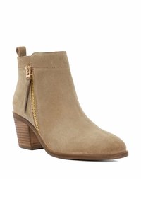 Tan suede ankle boot with a stacked wooden heel, side zipper, and pull tab. Smooth texture and streamlined design.