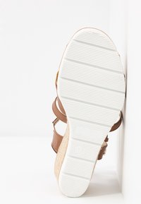 Sandale à semelle compensée avec semelle blanche texturée, lanières en cuir marron et talon espadrille tissé, taille 37, positionnée sur fond blanc.