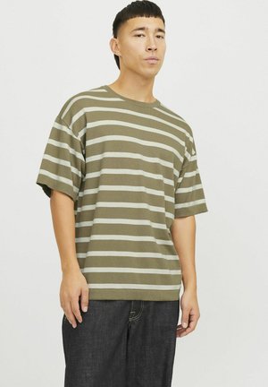 Camiseta de rayas verde oliva con un corte relajado, que presenta rayas horizontales de color beige claro y mangas cortas. Combinada con jeans de mezclilla oscuros.