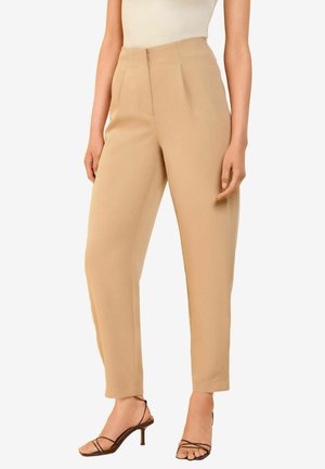 Pantaloni beige a vita alta con pieghe, dalla linea dritta e gamba affusolata. Tessuto liscio con finitura opaca. Indossati con sandali con tacco a stiletto e cinturini.