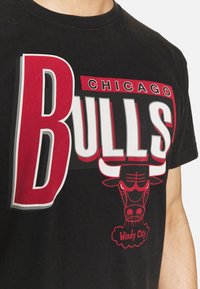 Zwart T-shirt met een gedurfde rode en witte grafische print van "Chicago Bulls" met een stierlogo en de tekst "Windy City" daaronder.