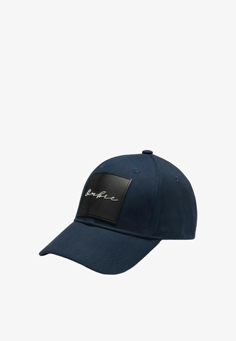 Casquette bleu marine en tissu avec une visière arrondie ; dotée d'un patch rectangulaire noir avec inscription blanche. Fermeture arrière ajustable.