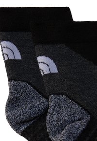 Czarno-szare skarpetki z geometrycznym wzorem, wykonane z miękkiego materiału o dzianinowej fakturze. Podkreślone jasnoszarymi kształtami.