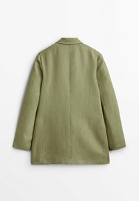 Olive green blazer made from a textured fabric. Features a notched collar and a straight cut, with a back vent for ease of movement.
