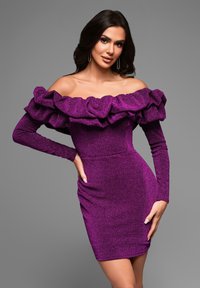 Violet off-the-shoulder mekko, jossa on rypytetty kaula-aukko ja pitkät, tiukat hihat. Valmistettu teksturoidusta, kimaltavasta kankaasta, joka korostaa hoikkaa siluettia.