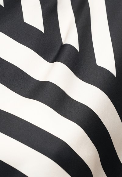 Ύφασμα με ασπρόμαυρες ρίγες και ομαλή υφή, που παρουσιάζει ελαφριές πτυχώσεις και καμπύλα σχέδια.