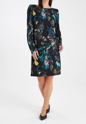 Abito nero con maniche lunghe, caratterizzato da un motivo floreale in turchese, giallo e grigio. Tessuto testurizzato, taglio dritto. Tacchi indossati con l'abito.
