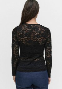 Zwarte kant lange mouwen top met een bloemenpatroon, een ronde halslijn en een klein zilveren hardware detail aan de achterkant.