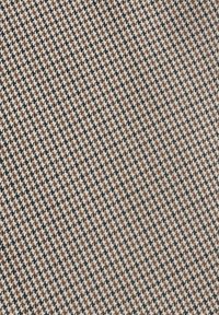 Motif de tissu pied-de-poule avec des petits carreaux noirs, blancs et marron alternés créant un design textile texturé et classique.