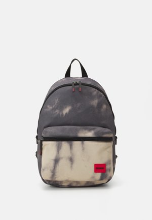 Grå og beige tie-dye rygsæk med lynlåslomme foran og rød HUGO-logo patch, sorte lynlåstræk og bærehåndtag på toppen.
