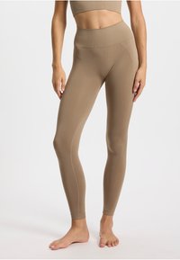 Leggings couleur sable avec une taille haute, un design sans coutures, et des coutures détaillées. Tissu doux et extensible avec une texture lisse.