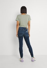 Grå kortärmad t-shirt, mörkblå slim-fit jeans och pastellfärgade sneakers. Minimalistisk design med en mjuk textur och subtila sömnadsdetaljer.
