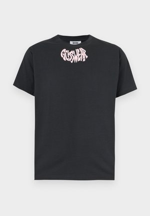 Črna majica s kratkimi rokavi in okrolim izrezom, z roza popačenim napisom "GCDS WEAR" natisnjenim blizu ovratnika spredaj.