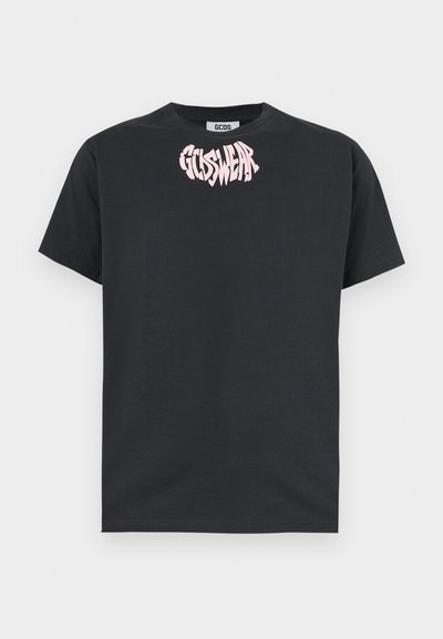 Μαύρο κοντομάνικο μπλουζάκι με στρογγυλή λαιμόκοψη και ροζ παραμορφωμένο κείμενο "GCDS WEAR" τυπωμένο κοντά στη λαιμόκοψη μπροστά.