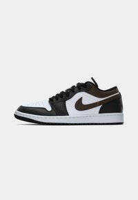 Nízkopoložené tenisky Nike v bielej, čiernej a hnedej farbe s čiernymi šnúrkami a hnedým logom swoosh na boku.