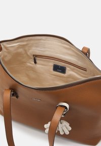 Sac à main en cuir marron avec une surface texturée, fermeture éclair et doublure beige. Il possède une petite poche intérieure et un charme décoratif.