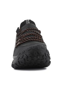 Chaussure de sport noire avec semelle en caoutchouc texturé, système de laçage à l'avant avec des fils orange et talon renforcé. Design épuré et minimal.