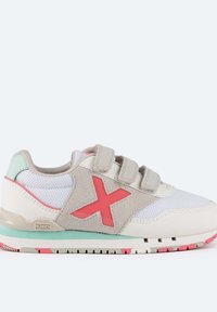 Zapatilla deportiva blanca y gris con acentos en rosa, parte superior de malla, correas ajustables de Velcro y una suela de goma texturada con un patrón multicolor.