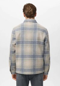 Karirana vuna jakna u bež i svijetlo plavoj boji, s ovratnikom i dugim rukavima, opuštenog kroja i dugmadi na manžetama.