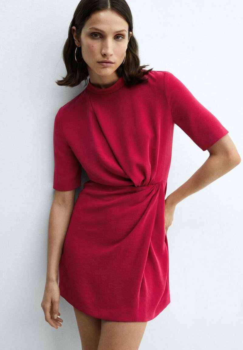 Červené šaty s krátkym rukávom a vysokým golierom, s prekrúteným detailom v oblasti pása, vyrobené z jemného materálu. Úzka silueta s hladkou textúrou.