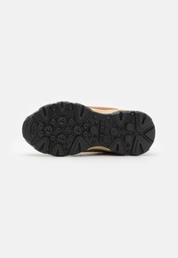 Baskets GEOX avec une semelle en caoutchouc noir, une tige marron et crème, présentant un design texturé et des perforations pour la respirabilité.