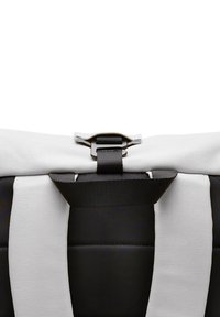 Sac noir et blanc avec des finitions en textile et lisses, doté d'une fermeture à boucle et d'un design à rayures horizontales, mettant en avant des textures contrastées.