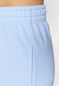 Ces joggers d'athlétisme bleu clair présentent un tissu texturé, une taille élastique et des poches latérales. Le design est décontracté et possède une coupe confortable.