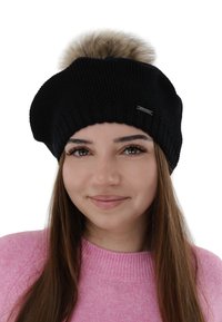 Berretto a cuffia nero lavorato a maglia con un grande pon pon in pelliccia sintetica sulla parte superiore e un accento con logo argentato. Tessuto morbido, risvolto a coste e design morbido.