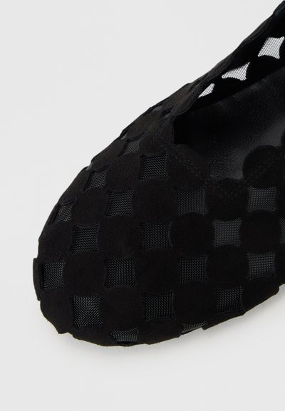 Black slip-on shoe featuring a woven upper of suede and mesh with a rounded toe. The design has a checker pattern and textured surface.