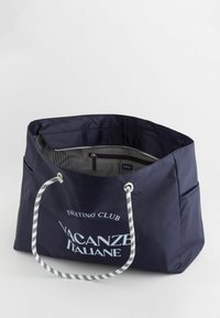 Laadukkaasta synteettisestä materiaalista valmistettu tummansininen olkalaukku, jossa on valkoiset köysikahvat. Sisäosassa on raidallinen vuori ja vetoketjullinen tasku.