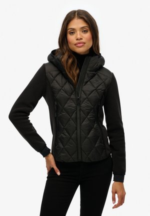 Zwarte jas met een geborduurde voorkant, capuchon en contrasterende fleece mouwen. Inclusief ritszakken en een slim fit ontwerp.