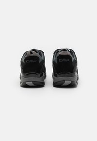 Schwarze und graue Sportschuhe verfügen über ein strukturiertes Obermaterial, eine gepolsterte Sohle und Logos an der Rückseite. Das Design umfasst eine abgerundete Zehenpartie und eine Ziehlasche an der Ferse.
