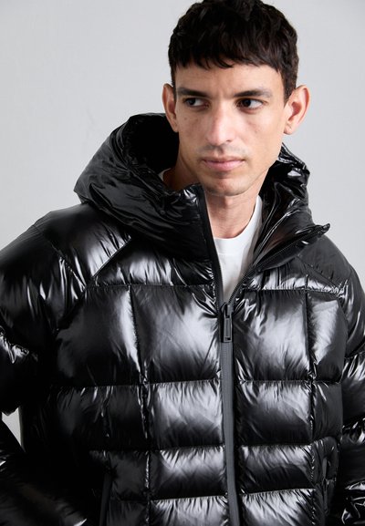 Giacca imbottita nera con finitura lucida, dotata di cappuccio, cuciture a zig zag e zip frontale. Design leggero con una texture morbida.
