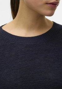Kraljevsko plavi pleteni pulover s okruglim izrezom koji ima rebrasti detalj i teksturiranu tkaninu. Pritvorni prikaz područja izreza i ovratnika.