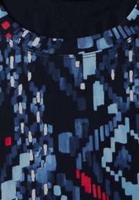 Marineblauwe stof met een geometrisch pixelpatroon in verschillende tinten blauw, wit en rood. Glad oppervlak met een ronde halslijn.
