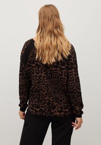 Sweter w brązowo-czarny wzór lamparta o luźnym kroju, z długimi rękawami i ściągaczami, wykonany z lekko teksturowanej dzianiny.