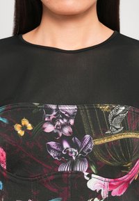 Black garment with a sheer upper section and a floral patterned lower section showcasing vibrant colors like purple, pink, and yellow.