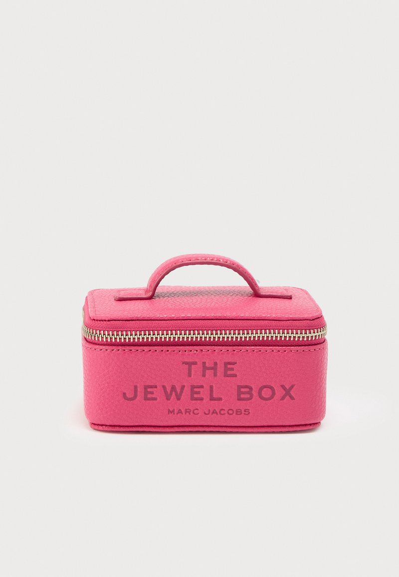 Rosa smykkeskrin i skinn med teksturert overflate, utstyrt med håndtak på toppen, metallglidelås og trykt tekst: "THE JEWEL BOX" og "MARC JACOBS."