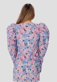 Blumenmusterkleid mit pastellrosa, blauen und weißen Blumen auf hellem Hintergrund, mit Puffärmeln und einer taillierten Silhouette.