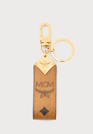 Breloc MCM din piele maro deschis cu accesorii aurii, logo gravat și inel pentru atașarea cheilor sau a accesoriilor.