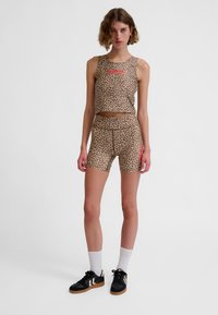 Set van een cropshirt en korte broek met luipaardprint in beige en bruin, met een rood logo, gemaakt van gladde stof, met een aansluitend ontwerp.